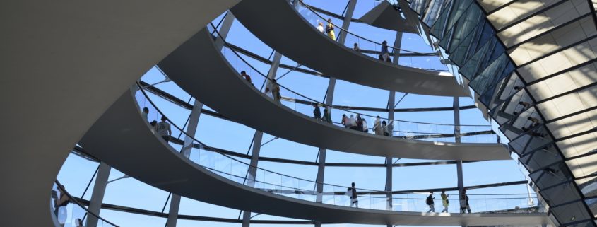 Zwischen den geschwungenem Aufgang in der Reichtagskuppel leuchtet der blaue Himmel durch die rechteckigen Fensterelemente